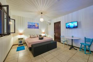 a bedroom with a bed and a table and a tv at Villa Carina Apartments in Kralendijk
