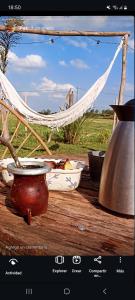 a picture of a table with a vase and a hammock at LAS CASUARINAS CABAÑA Spa in Carmen de Areco