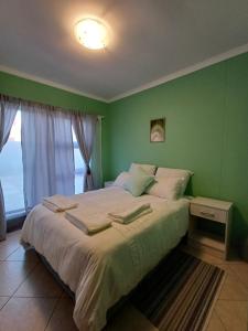 a bedroom with a large bed with a green wall at The Columbine Holiday Home in Swakopmund