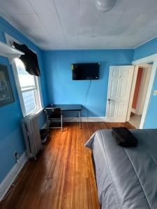 a bedroom with blue walls and a bed and a desk at Fidelia Emerald Room Queen Bed within minutes of Newark Liberty International Airport and Newark Penn Station in Irvington