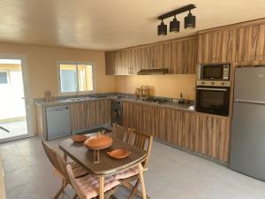 Una cocina con una mesa con sillas y un refrigerador. en Dar Kbira, en Dar Bouazza
