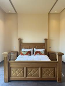 Un dormitorio con una gran cama de madera con almohadas. en Dar Kbira, en Dar Bouazza