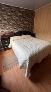 a bedroom with a bed and a brick wall at Cabañas ROMA, entre volcanes in Puerto Varas