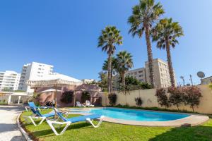 a swimming pool with two chairs and palm trees at De La Costa Cabañas in La Serena