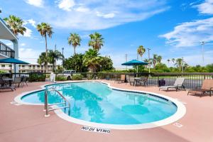 Una piscina en un resort con muebles de patio y palmeras. en Best Western Lake Okeechobee, en Okeechobee