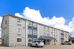 a large building with two cars parked in a parking lot at SureStay Hotel by Best Western Groves in Groves