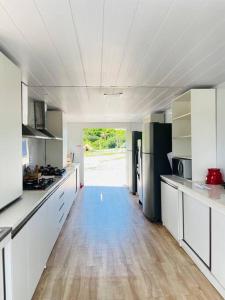 una grande cucina con mobili bianchi e pavimento in legno di Arteco Camp a Baía Formosa