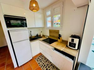 a small kitchen with white cabinets and a microwave at Maison T3 - Vue sur la Baie du Marin, Piscine in Le Marin