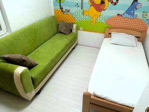 a room with a green couch and a bed at Historia Hostel in Skopje