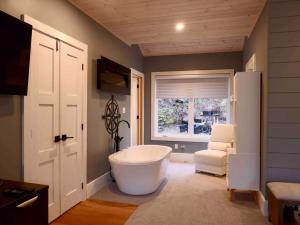 a bathroom with a tub and a chair and a window at The Rowanwood - Muskoka Cottage Retreat in Huntsville +73 photos