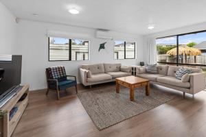 a living room with a couch and a table at The Summer Pad - Omaha Holiday Home in Warkworth