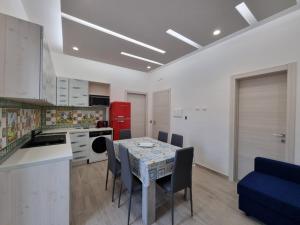 cocina con mesa, sillas y nevera roja en Maria Blue House, en Portopalo di Capo Passero