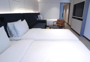 a bedroom with a large white bed and a chair at Hotel PJ Myeongdong in Seoul