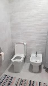 a white bathroom with a toilet and a sink at Parkentskaya 170 Tashkent apartment by RNB estate in Yalanghoch +2 photos