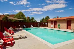 una piscina con sillas rojas y una valla en Fairway Foothills #3335, en Moab