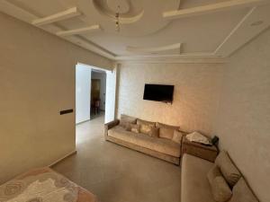 a living room with a couch and a tv on the wall at Dahomey plage appartement Dahomey city in Bouznika