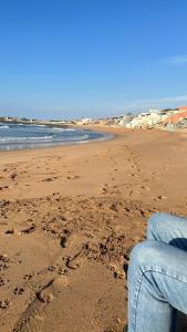 a person sitting on a beach with footprints in the sand at Dahomey plage appartement Dahomey city in Bouznika