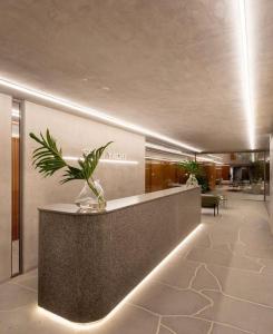 eine Lobby mit einer Theke mit einer Pflanze darauf in der Unterkunft Setai Yacth, Flat para até 03 pessoas a beira mar do Cabo Branco in João Pessoa