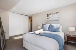 a bedroom with a large bed with blue pillows at Sun filled & Spacious with Ocean Views & beach in Mount Maunganui