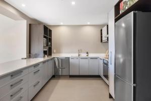 a kitchen with white cabinets and a stainless steel refrigerator at Sun filled & Spacious with Ocean Views & beach in Mount Maunganui +26 photos