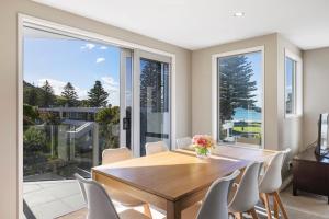 a dining room with a table and chairs and a large window at Sun filled & Spacious with Ocean Views & beach in Mount Maunganui