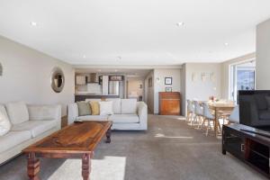 a living room with a couch and a table at Sun filled & Spacious with Ocean Views & beach in Mount Maunganui