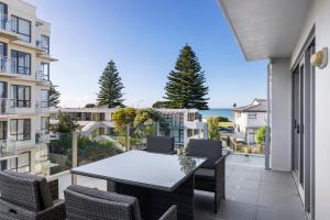 a balcony with a table and chairs and the ocean at Sun filled & Spacious with Ocean Views & beach in Mount Maunganui