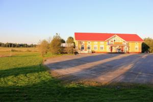 a large yellow building with a red roof in a field at Koskikievari in Lappajärvi