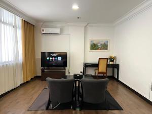 a living room with a tv and a table and chairs at Remington Hotel in Muar