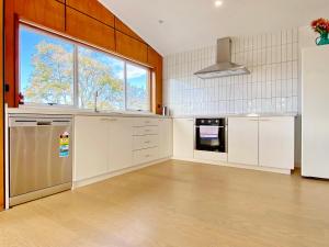 a large kitchen with white cabinets and a large window at Waterfront villa near IKEA and Sylvia Park in Auckland