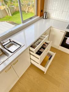 a kitchen with white cabinets and a sink and a window at Waterfront villa near IKEA and Sylvia Park in Auckland +37 photos