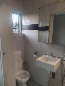 a white bathroom with a toilet and a sink at 3-bedroom Deluxe Apartment in Nadi +14 photos