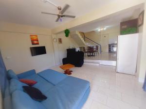 a living room with a blue couch and a kitchen at 3-bedroom Deluxe Apartment in Nadi