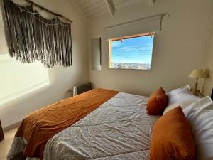 une chambre avec un lit avec des oreillers orange et une fenêtre dans l'établissement TAAR AIKE II (Lugar de Hielo), à El Calafate