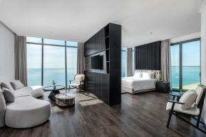 a hotel room with a bedroom and a bed and a couch at Awaken Da Nang Hotel in Danang