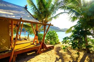 a porch swing on a beach with the ocean at Barefoot Kuata Island Resort in Kuata +68 photos