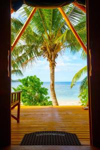 a view of the beach from a porch with a palm tree at Barefoot Kuata Island Resort in Kuata