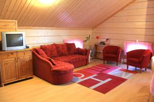 sala de estar con sofá rojo y 2 sillas en Koskikievari, en Lappajärvi