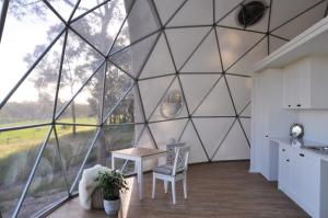 a room with a large glass wall with a table and chairs at Mile End Glamping Pty Ltd in Yelverton