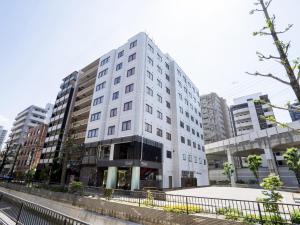 a white building in a city with tall buildings at Hotel New Gaea Yakuin in Fukuoka