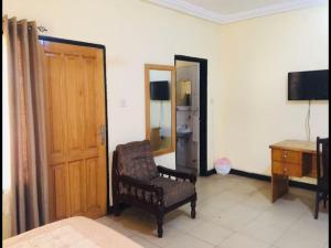 a room with a chair and a desk and a television at Double Room With Balcony in the heart of city in Accra