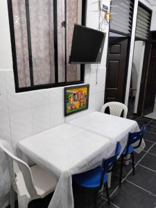 a white table with chairs and a tv on the wall at Alojamiento en villavicencio con parqueadero in Villavicencio