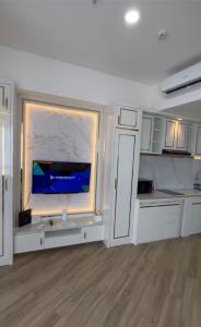 a kitchen with white cabinets and a large tv on a wall at The Bay Apartemen Deluxe Lampung City Mall in Kuala +10 photos
