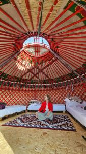 a woman sitting on a bed in a yurt at AiSun Eco Yurt Camp in Tossor