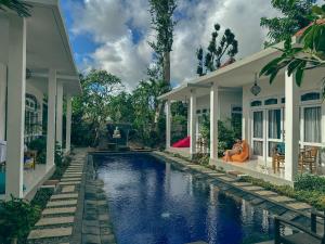 a house with a swimming pool in front of a house at Bali Stuti Jimbaran Inn in Jimbaran