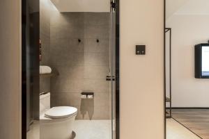 e bagno con servizi igienici e porta doccia in vetro. di Atour Hotel Yantai Penglai Government Centre a Penglai