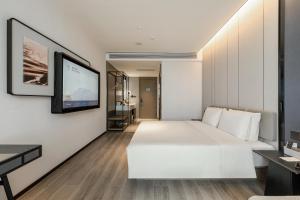 una camera con letto bianco e TV a schermo piatto di Atour Hotel Yantai Penglai Government Centre a Penglai