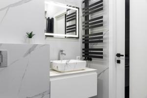 een witte badkamer met een wastafel en een spiegel bij RentWill apartments Silver in Chişinău