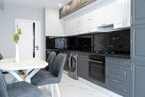 een keuken met witte kasten en een tafel en stoelen bij RentWill apartments Silver in Chişinău