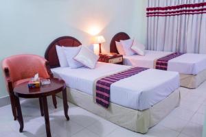 a hotel room with two beds and a chair at Meridian Hotel & Restaurant in Chittagong